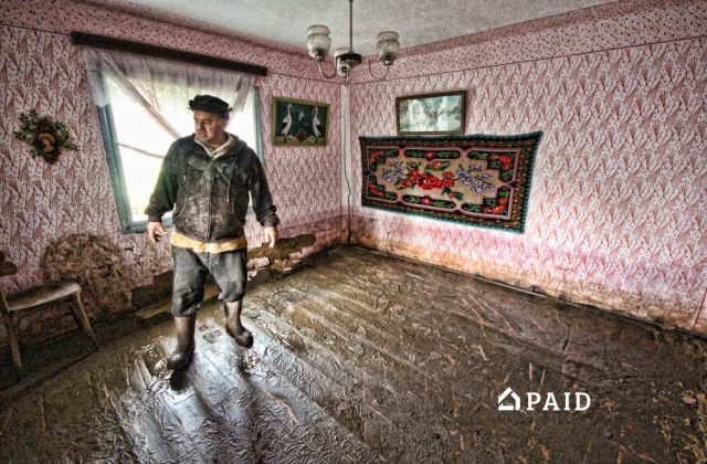 Descumpănit, proprietarul unei case pline de noroi după o inundație